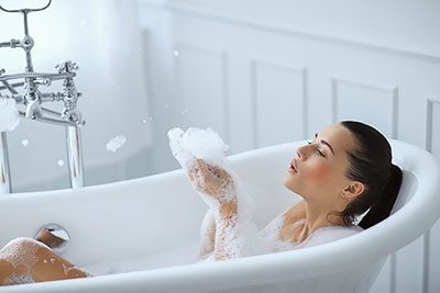 Jeune femme dans un bain avec de la mousse